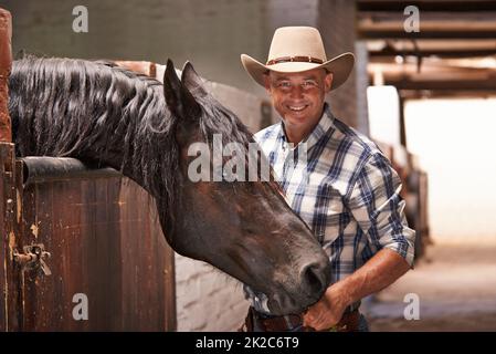 Es ist Zeit für eine Fahrt. Eine fürsorgliche Ranch Hand, die sich um ein Pferd im Stall kümmert. Stockfoto