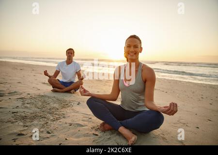 Lassen Sie sich von der Natur wiederherstellen. Portrait eines Paares, das bei Sonnenuntergang am Strand Yoga macht. Stockfoto