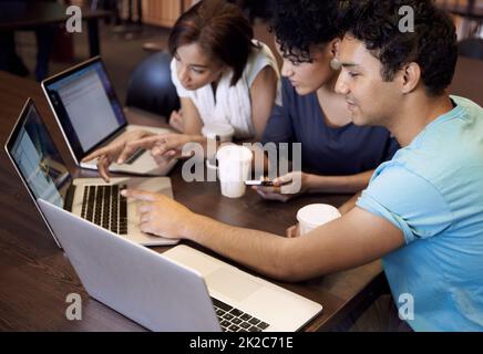 Dynamik der Studiengruppe. Eine Gruppe von Studenten, die einen Laptop verwenden, um eine Gruppenaufgabe abzuschließen. Stockfoto