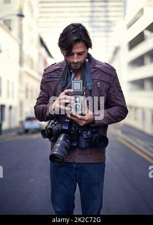 Fotografie ist meine Leidenschaft. Aufnahme eines hübschen jungen Fotografen bei der Arbeit in der Stadt. Stockfoto