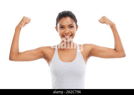 Sie zeigt ihre Muskeln. Eine junge Frau in Turnkleidung, die ihre Arme beugend. Stockfoto