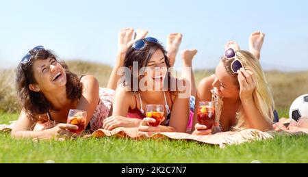 Tolle Freundinnen. Eine Gruppe von Freunden, die draußen auf einer Decke liegen und zusammen einen Drink genießen. Stockfoto