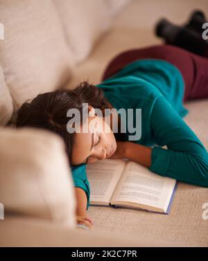 Wir hören nie auf, Geschichten aus dem Schlafengehen zu genießen. Ausgeschnittene Aufnahme einer jungen Frau, die mit einem Buch auf dem Sofa schlaft. Stockfoto