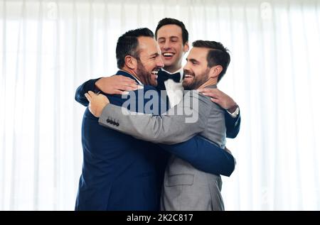 Gesegnet, sie an diesem besonderen Tag bei mir zu haben. Aufnahme von zwei Groomsmen, die auf seinem Hochzeitsweg mit dem Bräutigam umarmen und feiern. Stockfoto