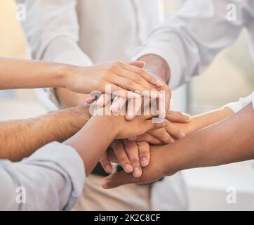 Auf drei. Eine ausgeschnittene Aufnahme einer nicht erkennbaren Gruppe von Geschäftsleuten, die sich im Büro zusammendrängten und ihre Hände in der Mitte auftürmen. Stockfoto