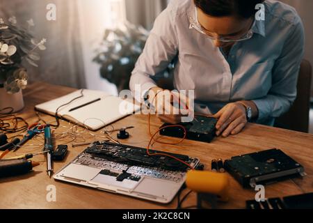 Shell hat diesen Laptop in kürzester Zeit einsatzbereit. Ausgeschnittene Aufnahme einer jungen Computertechnikerin, die in ihrer Werkstatt einen Laptop repariert. Stockfoto