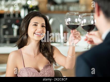 Heres to watching our love grow. Aufnahme eines glücklichen jungen Paares, das bei einem romantischen Date in einem Restaurant mit Wein röste. Stockfoto