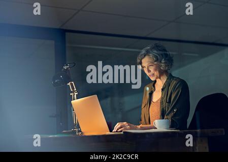 Man braucht eine unermüdliche ethnische Arbeit, um erfolgreich zu sein. Eine kurze Aufnahme einer reifen Geschäftsfrau, die spät in einem Büro mit einem Laptop arbeitet. Stockfoto