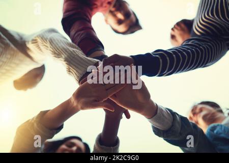 Wahre Freunde bleiben zusammen. Low-Angle-Aufnahme einer Gruppe von Studenten, die sich solidarisch in die Hände schlossen. Stockfoto