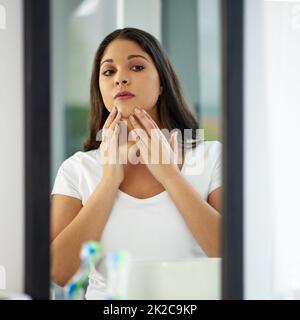 Auf Flecken prüfen. Aufnahme einer attraktiven jungen Frau, die sich in ihrem Badezimmer fertig macht. Stockfoto