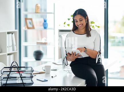 Geschäfte mit nur wenigen Handgriffe. Aufnahme einer jungen Geschäftsfrau, die in einem Büro ein digitales Tablet benutzt. Stockfoto