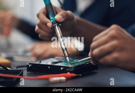 Der Meister bei der Arbeit mit jeder Computerhardware. Schuss eines Technikers, der einen Lötkolben benutzt. Um die Computerhardware zu reparieren. Stockfoto