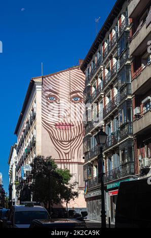 Großes Wandgemälde mit dem Gesicht einer Frau hoch auf der externen Parteiwand des Gebäudes, Calle de la Magdalena, Madrid, Spanien. Stockfoto