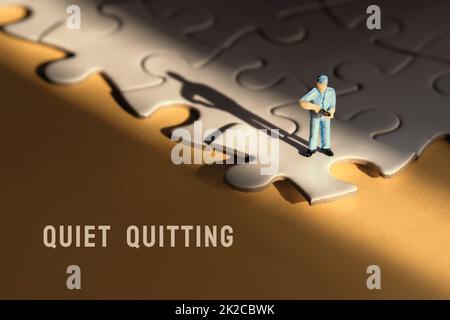 Konzept des ruhigen Aufenschens, Job Burnout, Depression. Einzelne kleine Arbeiter Miniatur-Figur am Rand des verknüpften blauen Puzzle. Gelber Papierhintergrund Stockfoto