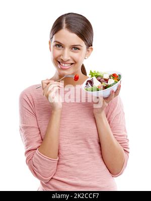 Frisch und lecker. Studioportrait einer schönen jungen Frau, die einen gesunden Salat isst. Stockfoto