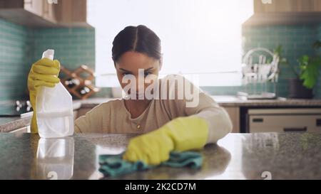 Ich muss jeden Punkt erreichen. Aufnahme einer jungen Frau, die zu Hause ihre Küchentheke abschrubbt. Stockfoto