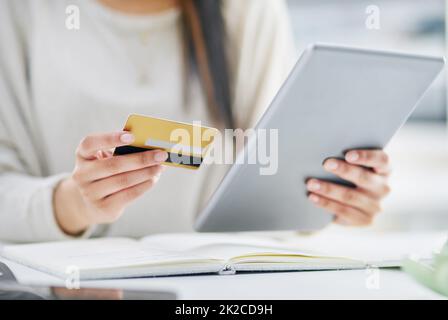 Machen Sie ein paar schnelle WIPE online. Nahaufnahme einer unkenntlichen Geschäftsfrau, die in einem Büro ein digitales Tablet und eine Kreditkarte verwendet. Stockfoto