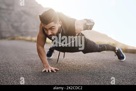 Übersteht jede Herausforderung und sie wird euch verändern. Aufnahme eines sportlichen jungen Mannes, der Liegestütze beim Training im Freien macht. Stockfoto