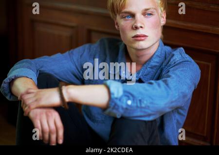 Brütende Jugend. Nachdenklicher und hübscher junger blonder Kerl mit sehr blauen Augen. Stockfoto