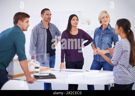 Ihre Ideen sind in Meetings immer willkommen. Ausgeschnittene Aufnahme einer Gruppe von Architekten, die Pläne diskutieren. Stockfoto