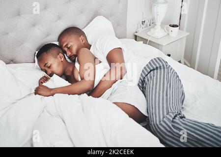 Unterschätzen Sie niemals die Kraft eines Nickernachens und Kuschelens. Aufnahme eines glücklichen jungen Paares, das zu Hause ein Nickerchen im Bett machte. Stockfoto