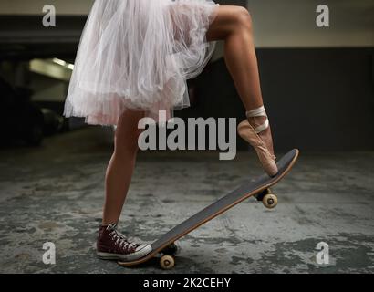 Ich habe viele Talente. Ein zugeschnittenes Bild einer Frau auf einem Skateboard, die einen Turnschuh und einen Ballettschuh trägt. Stockfoto