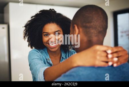 Hes my everything. Porträt eines fröhlichen jungen Paares, das sich gegenseitig hält und tagsüber einen zarten Moment in der Küche zu Hause teilt. Stockfoto