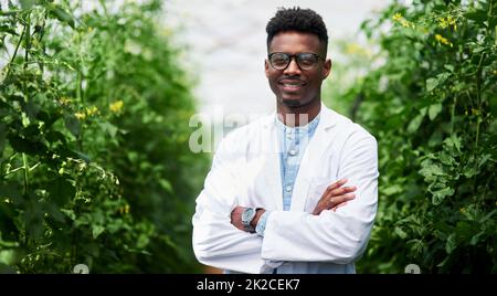 Pflanzen sind lebende Organismen, die sich wie wir alle kümmern müssen. Porträt eines hübschen jungen Botanikers, der mit seinen Armen im Freien in der Natur posiert. Stockfoto