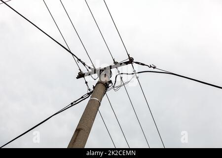 Kleine konkrete Säule mit Stromleitungen, bewölkten Himmel im Hintergrund. Stockfoto