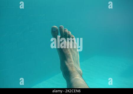 Unterwasser Foto-man's single Fuß mit Hellblau Schwimmbad Kacheln im Hintergrund. Stockfoto