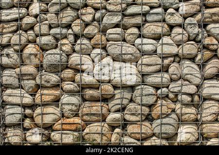 Wand aus runden Felsen, gesichert mit Stahldraht net (Eisen Stein Gabione) Stockfoto