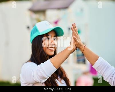 Wir sind Profis. Aufnahme einer fröhlichen jungen Frau, die einer anderen Person tagsüber eine hohe fünf bescheren soll. Stockfoto