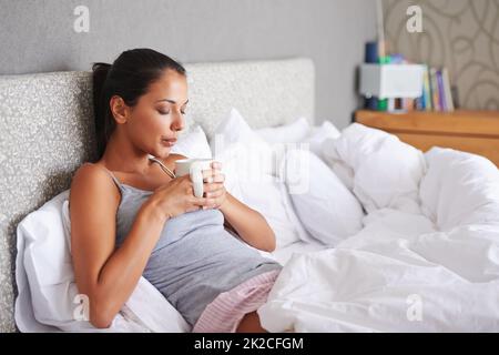 Einfach unvergleichlich... eine Tasse Kaffee am Morgen. Attraktive junge Frau bläst den heißen Dampf aus ihrem Morgenkaffee. Stockfoto