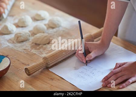 Gute Dinge sollen geteilt werden. Eine Frau, die ein Rezept für den Teig, der shes Vorbereitung schreibt. Stockfoto