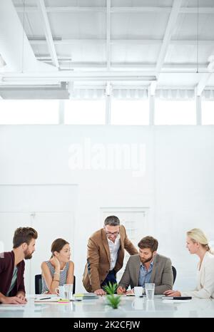 Brainstorming für zukünftigen Erfolg. Eine Gruppe von Mitarbeitern, die um einen Tisch stehen. Stockfoto