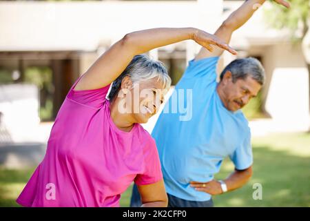 Bleiben Sie in unseren älteren Jahren geschmeidig. Aufnahme eines reifen Paares, das gemeinsam in ihrem Hinterhof trainiert. Stockfoto