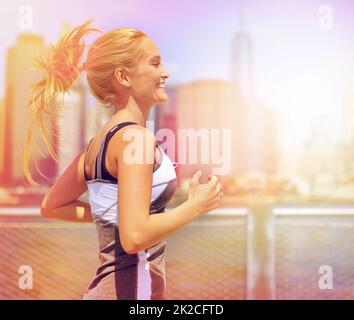 Auf einem lustigen Lauf in der Stadt. Aufnahme einer attraktiven Frau, die auf einer Promenade läuft. Stockfoto