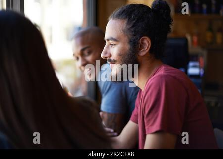 Freunde und ein kalter - das Leben ist gut. Eine kurze Aufnahme von jungen Freunden, die sich an einer Bar unterhalten. Stockfoto