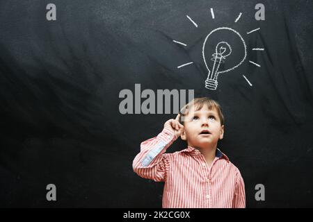 HES hat viele Ideen. Studioaufnahme eines Jungen mit einer kreidezeichnenden Glühbirne über seinem Kopf. Stockfoto