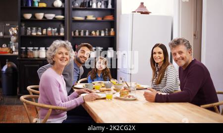 Beginnen Sie den Tag mit Angehörigen. Porträt einer Familie, die am Küchentisch frühstückte. Stockfoto