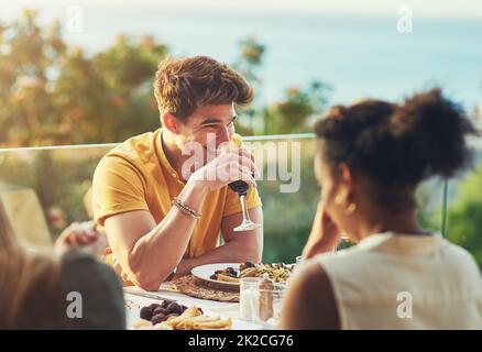 Wenn nur diese Art von Momenten ewig dauern können. Aufnahme eines gutaussehenden jungen Mannes, der ein Glas Wein genießt, während er mit Freunden draußen an einem Tisch sitzt. Stockfoto