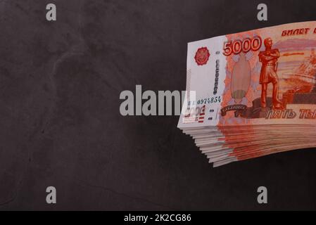 Russischer Rubel mit einem großen Bündel auf grauem Hintergrund. Ein Bündel 5000 Rubel-Noten. Stockfoto