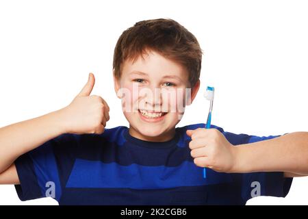 Die Dentalhygiene zieht die Daumen nach oben. Porträt eines Jungen, der eine Zahnbürste hält und einen Daumen nach oben gibt. Stockfoto