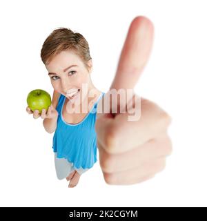 Sagen Sie ja zu gesunder Ernährung. Aufnahme einer jungen Frau, die vor weißem Hintergrund einen Apfel isst. Stockfoto