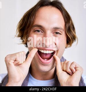 Stellen Sie sicher, dass Sie zwischen diese Zähne gelangen. Schuss eines jungen Mannes, der seine Zähne mit Zahnseide einmachte. Stockfoto