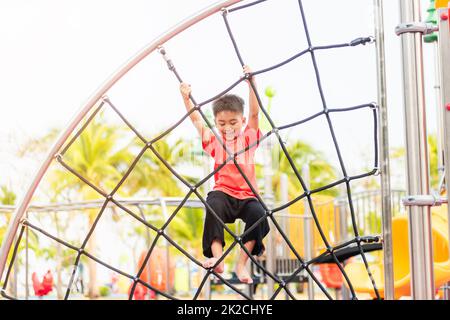 Asiatisches Kind lächelt beim Klettern draußen auf dem Spielplatz Stockfoto