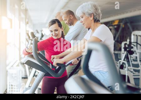 Fitness-Trainer im Fitnessstudio hilft älteren Menschen Stockfoto