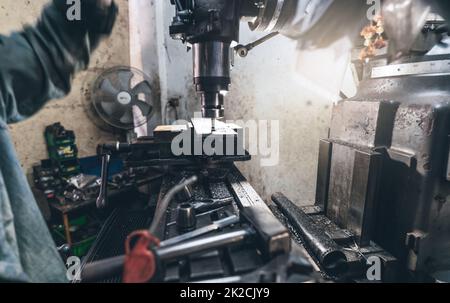 Selektiver Fokus auf Fräsmaschinen. Unscharfer Arbeiter arbeitet an der Fräsmaschine bis zum Fräsen von Metallplatten. Werkzeug für geschnittenes Metallwerkstück. Stahlfabrik. Fräsvorgang. Maschine in der Werkstatt Stockfoto