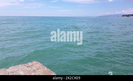 Blick vom Seepier auf den Wasserbereich des Strandes mit restriktiven Sicherheitsbojen und Booten im Hintergrund, das Konzept eines Badeurlaubs Stockfoto