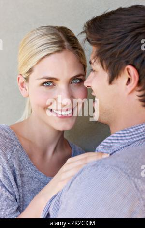 Verliebt in das Leben. Porträt eines liebevollen jungen Paares, das vor grauem Hintergrund steht. Stockfoto